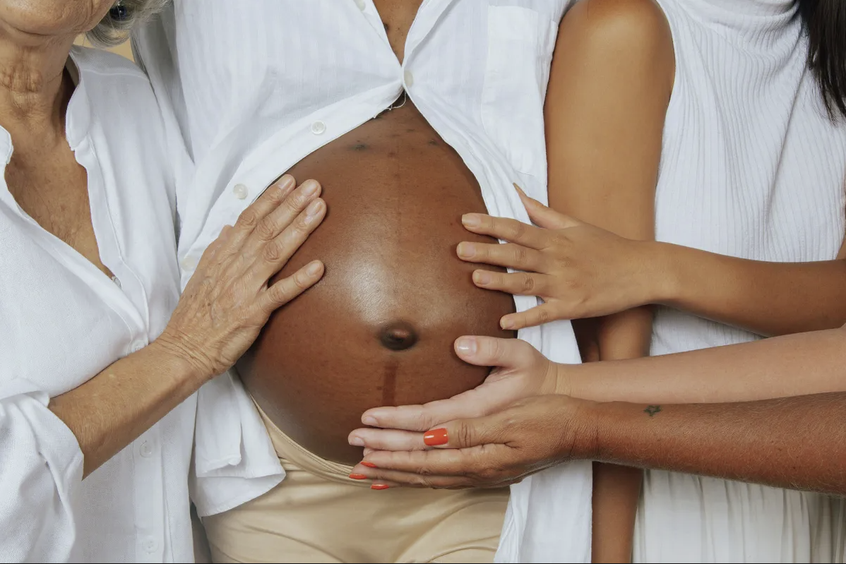 Family's hands resting on a pregnant belly